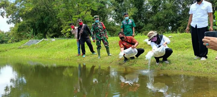 Bersama Kabid Perikanan, Anggota Satgas TMMD Bojonegoro Melepaskan Benih Ikan